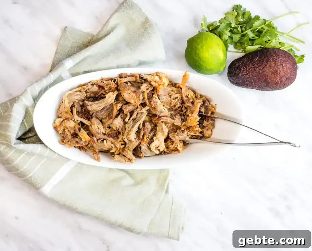 31 Slow Cooker Recipes to Walk In and Find Dinner Waiting 26 Al Pastor Carnitas in a white bowl with tongs.