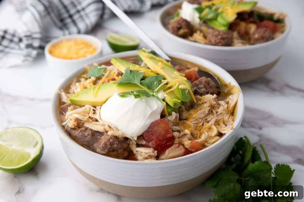 31 Slow Cooker Recipes to Walk In and Find Dinner Waiting 32 Two bowls of Slow-Cooker Taco Soup next to sliced lime.