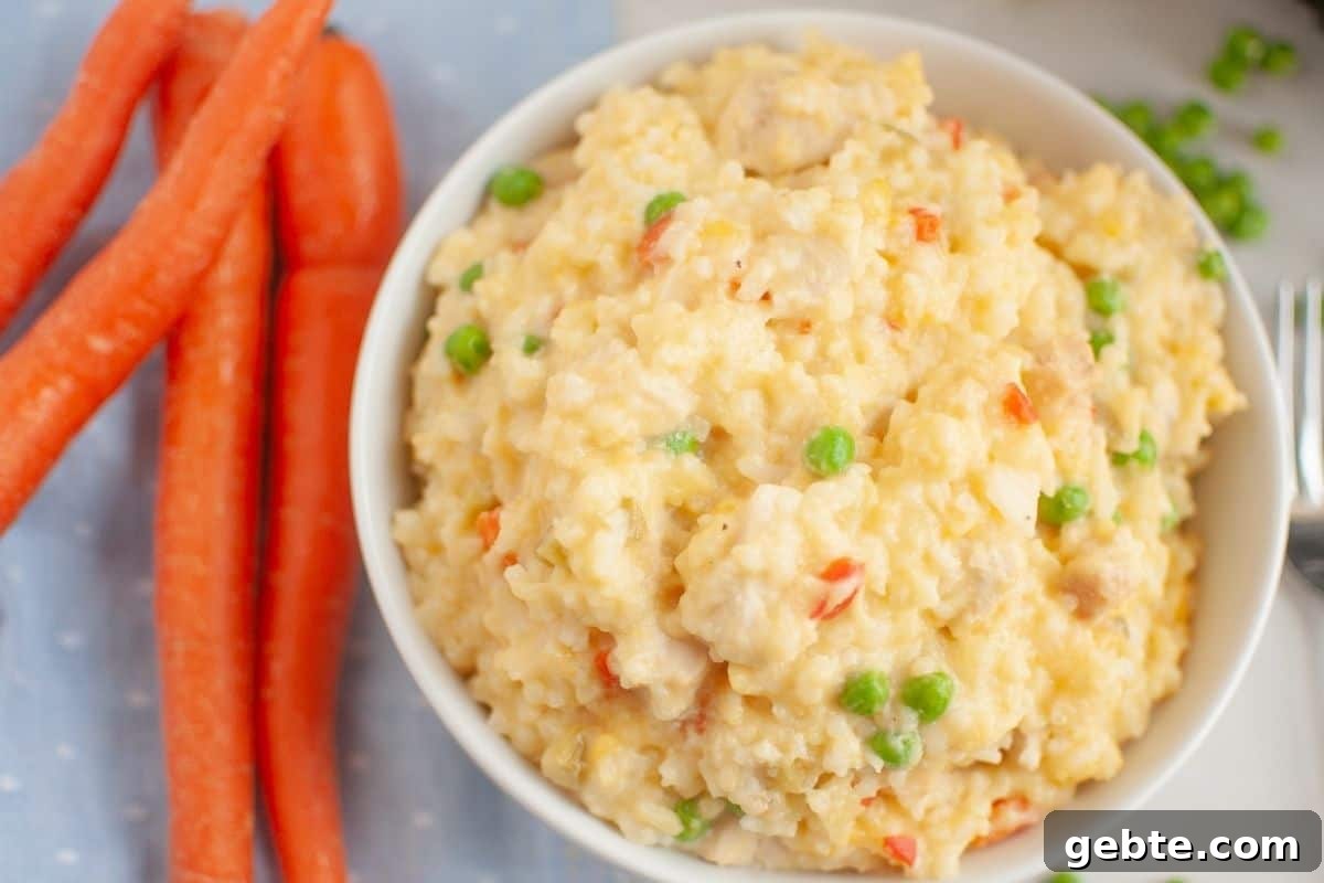 31 Slow Cooker Recipes to Walk In and Find Dinner Waiting 5 A bowl of Slow Cooker Chicken and Rice is next to whole carrots on a light blue cloth.