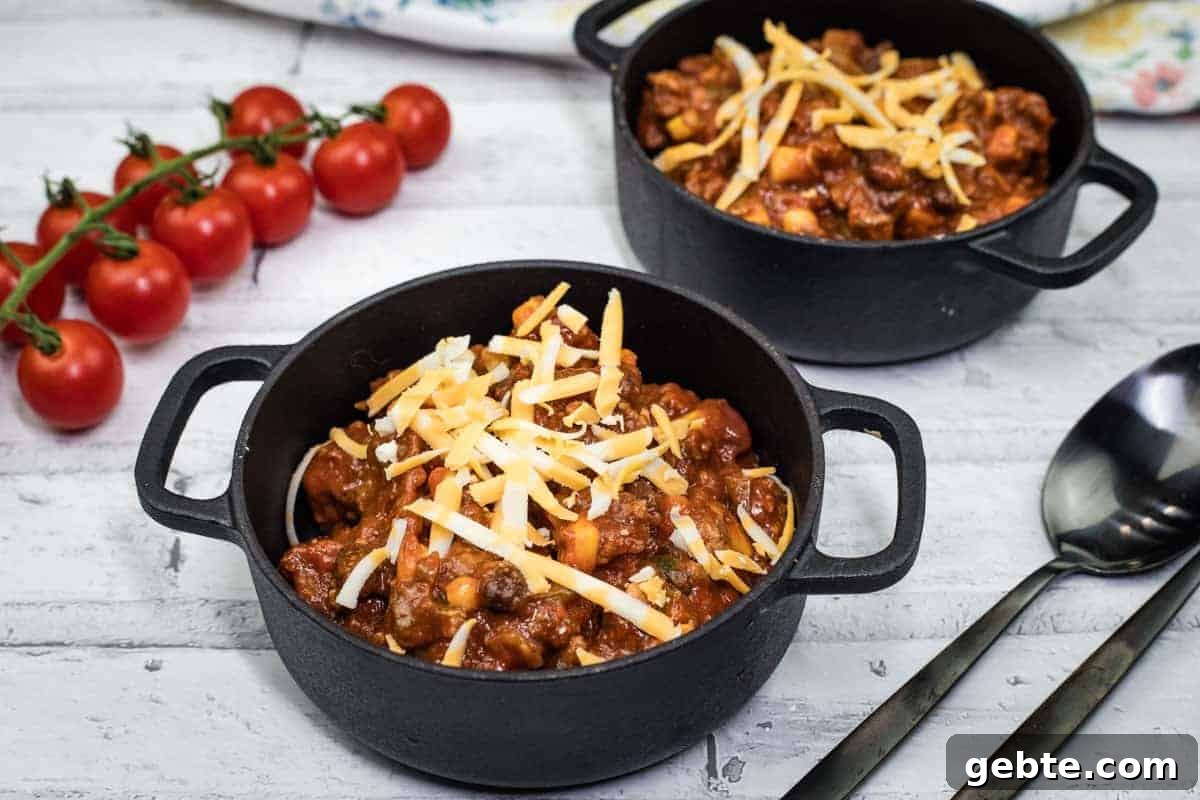 31 Slow Cooker Recipes to Walk In and Find Dinner Waiting 6 Two black pots of Slow Cooker Southwestern Chili topped with shredded cheese.