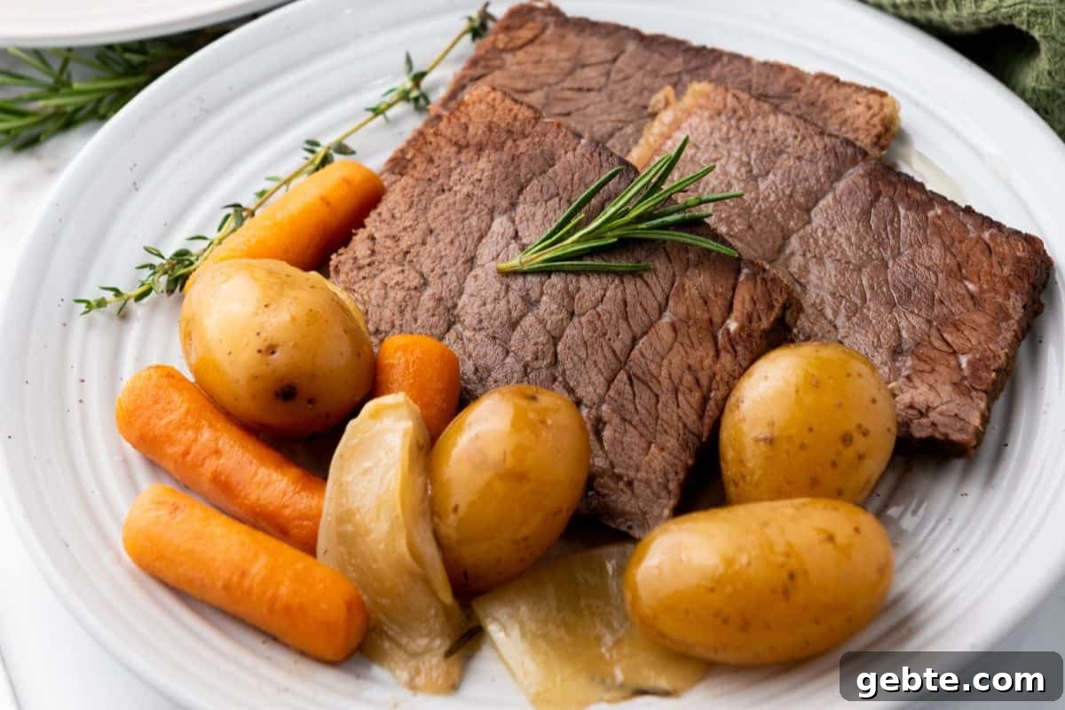 31 Slow Cooker Recipes to Walk In and Find Dinner Waiting 8 A plate of slow cooker rump roast with potatoes, carrots, onions, and a sprig of rosemary on a white dish.