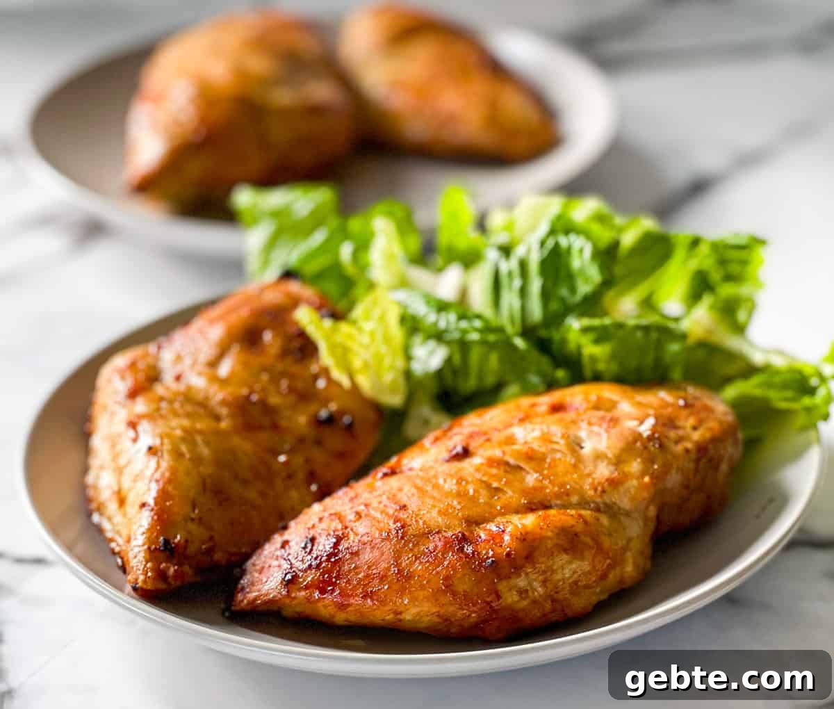 Juicy chicken breasts on a plate with a side of green salad.