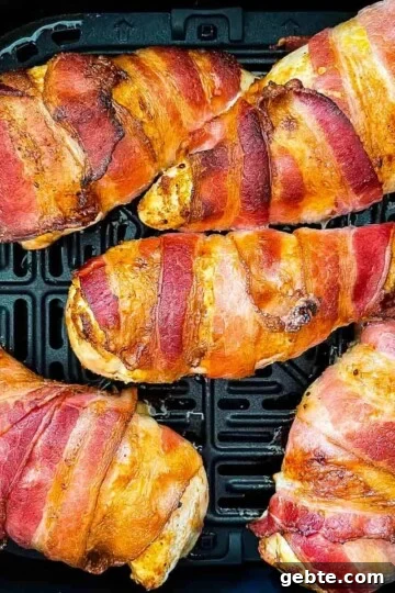 Cooked bacon-wrapped chicken in the air fryer basket.