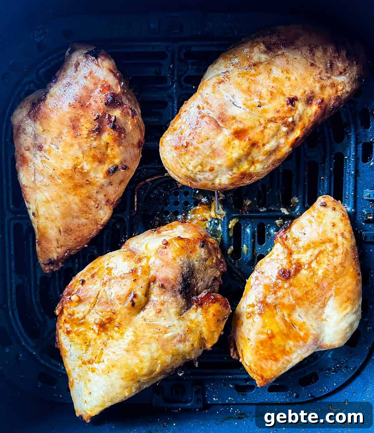 Air fried chicken breasts in the air fryer basket.