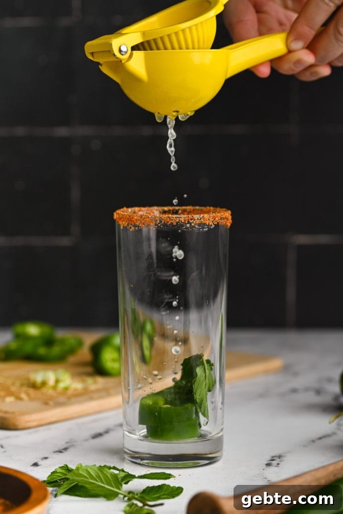 Using a handheld citrus juicer to add lime juice to spicy mojito.