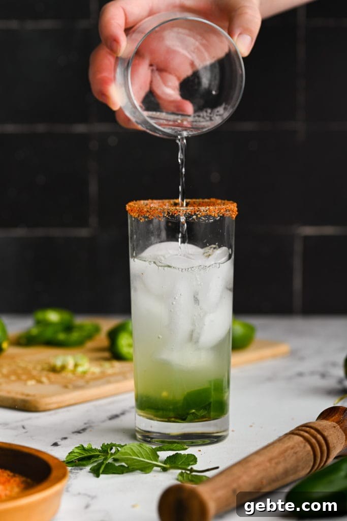Adding club soda to mojito with jalapeno to give it bubbles.