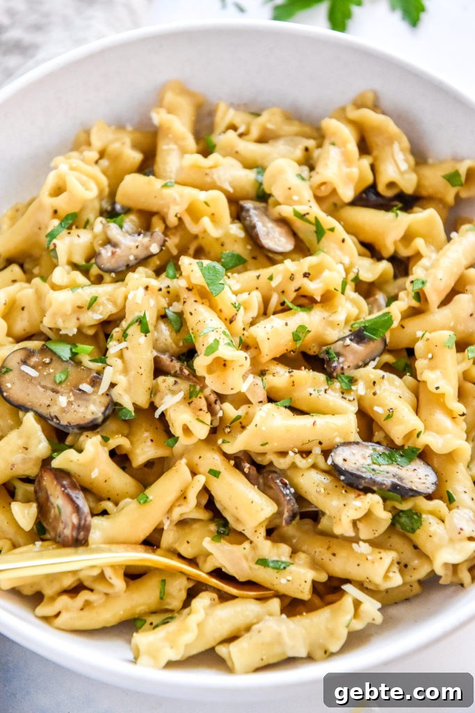 one pot creamy mushroom pasta in a white bowl with gold fork.