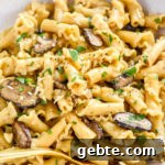 one pot creamy mushroom pasta in a white bowl with gold fork.
