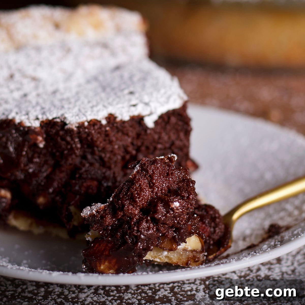 Decadent Chocolate Almond Pie Recipe — Crispy Crust & Rich Filling 3 Someone using a fork to cut a bite of chocolate almond pie from a slice on a white plate.