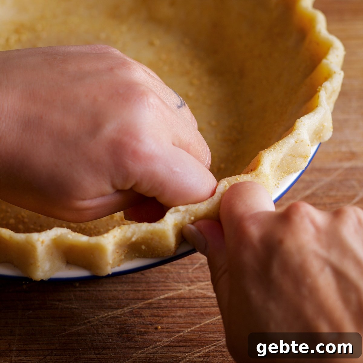 Decadent Chocolate Almond Pie Recipe — Crispy Crust & Rich Filling 6 Someone using their fingers to crimp the edges of a pie crust inside a pie plate.
