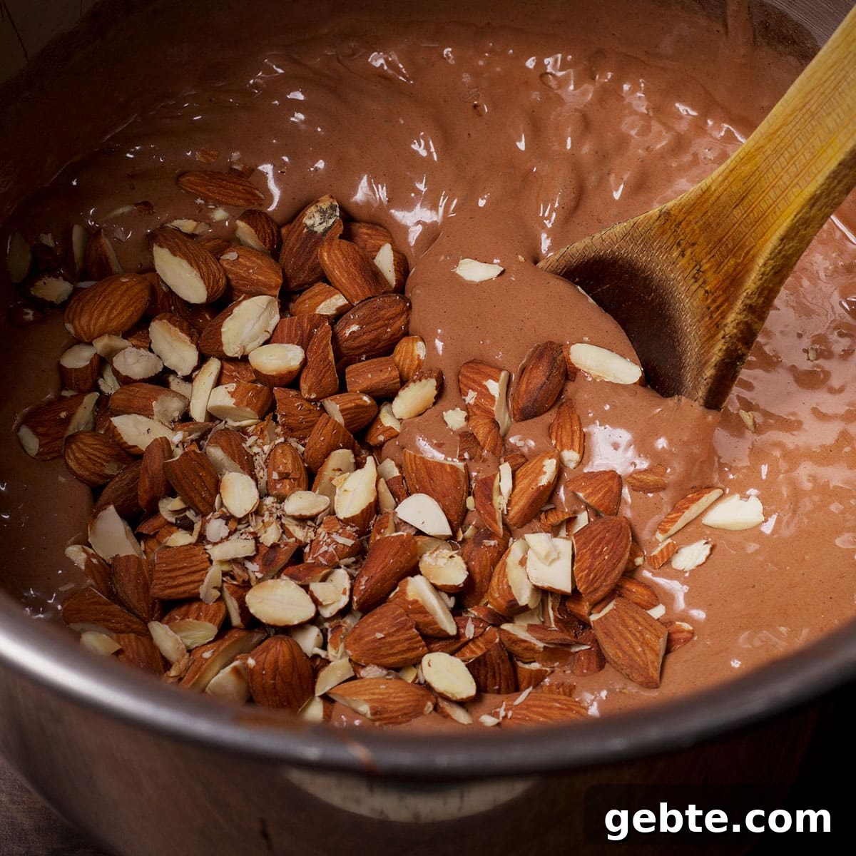 Decadent Chocolate Almond Pie Recipe — Crispy Crust & Rich Filling 10 Using a wooden spoon to stir chopped almonds into chocolate pie batter.