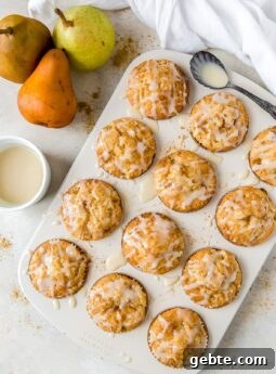 glazed ginger pear muffins in a muffin tin; pears next to muffin tin