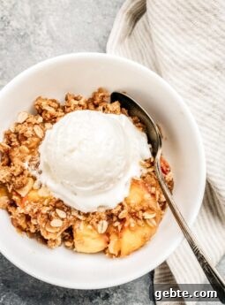 bowl of peach crisp, scoop of vanilla ice cream