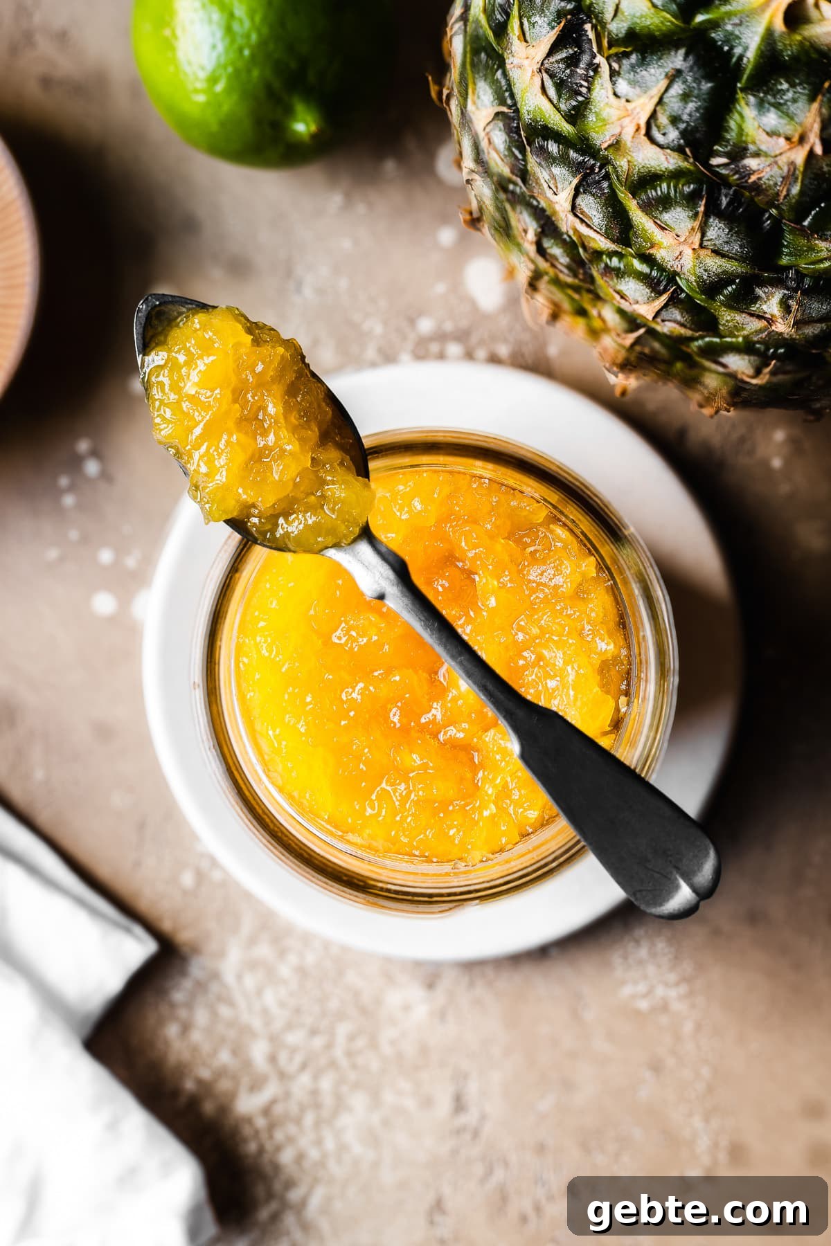 A spoonful of jam resting atop a jar of jam on a small plate.