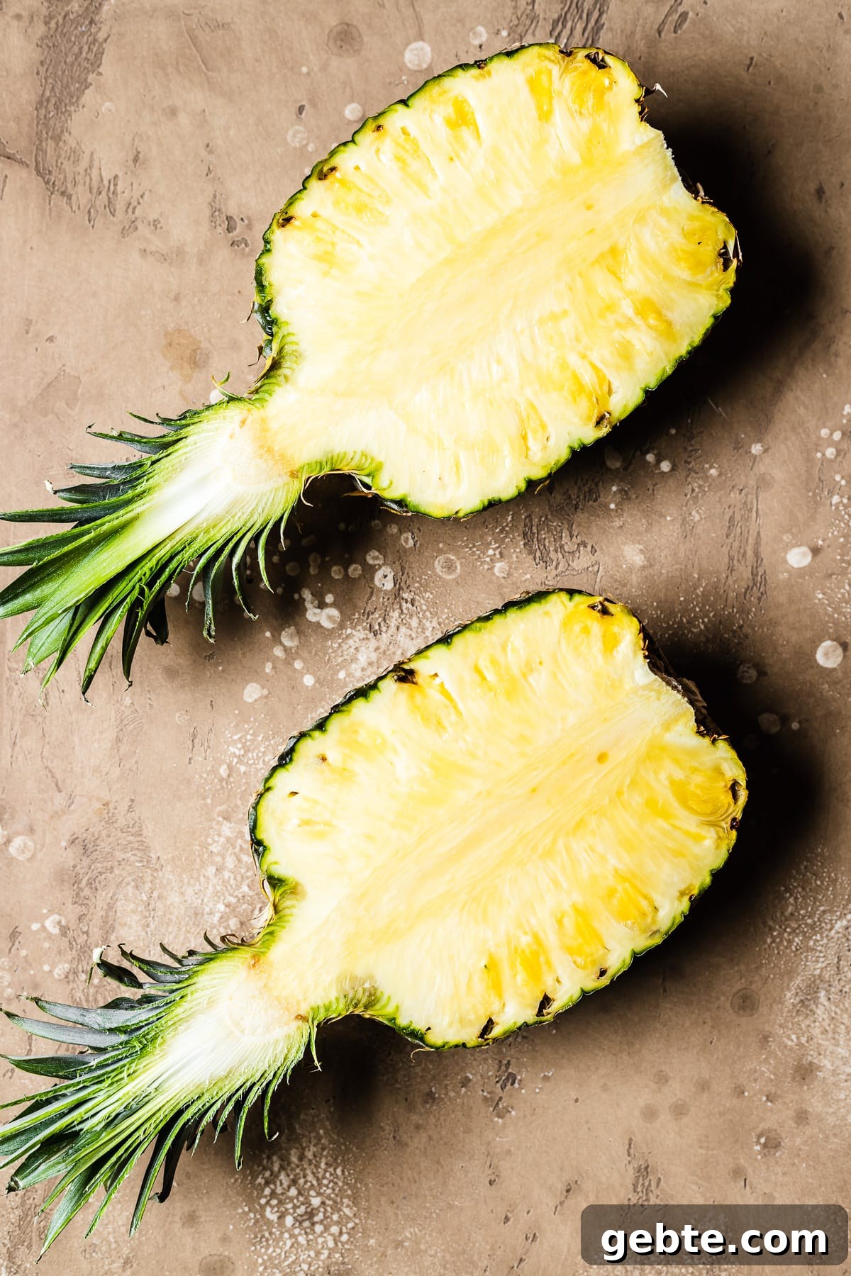 A pineapple split in half with the centers facing upwards.