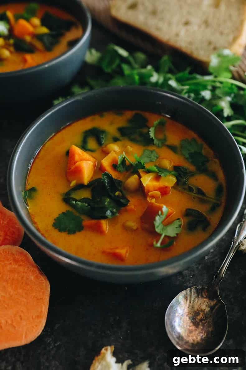 Creamy Curried Sweet Potato Soup Recipe for Cozy Dinners 2 curried sweet potato soup in a blue bowl with garbanzo beans, swiss chard and cilantro.