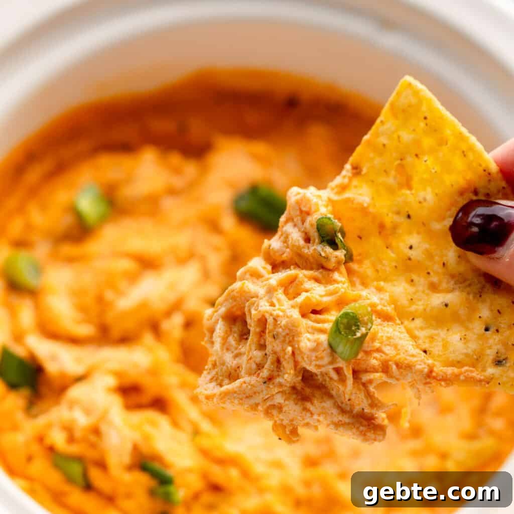 A chip with buffalo chicken dip on it coming out of a crockpot
