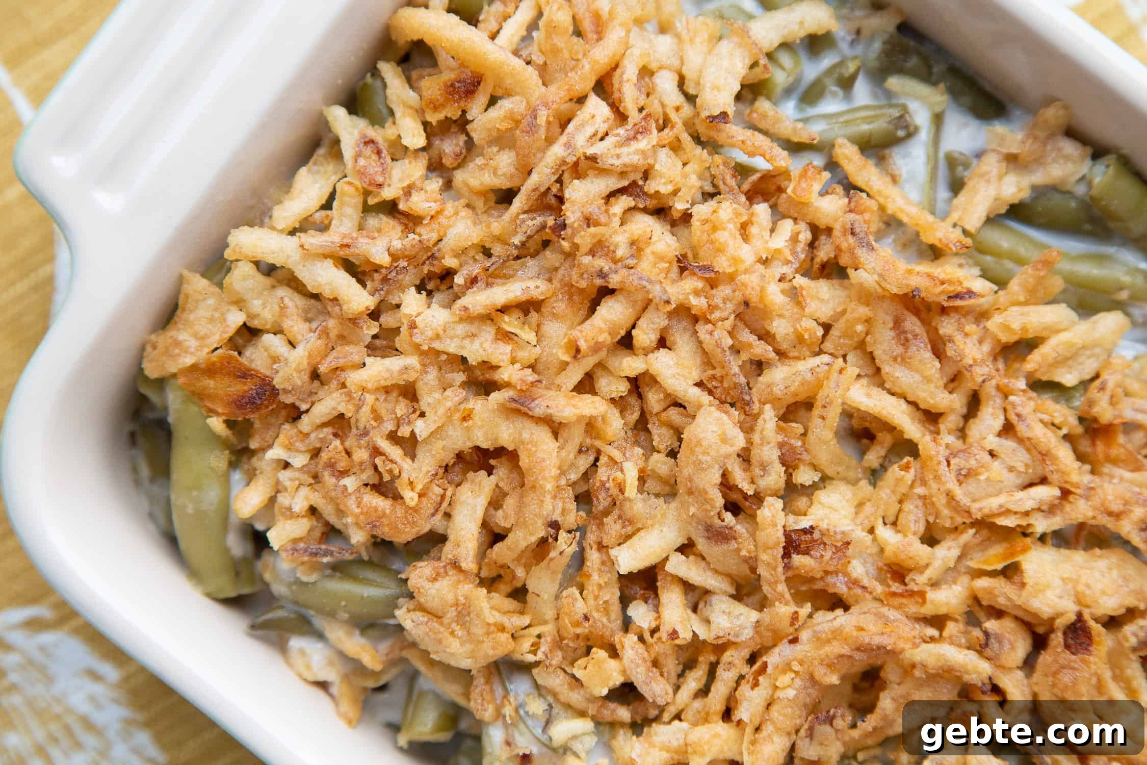 green bean casserole topped with fried onions in a casserole dish.