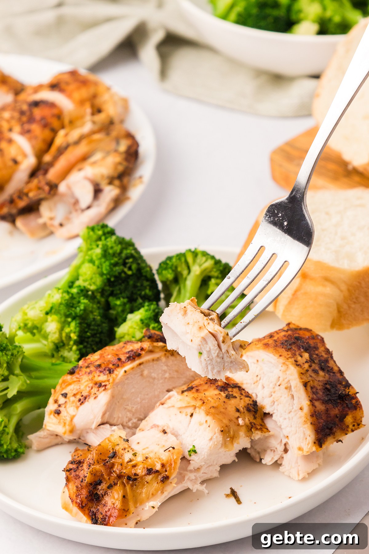 Sliced pieces of chicken on a plate with broccoli and bread.