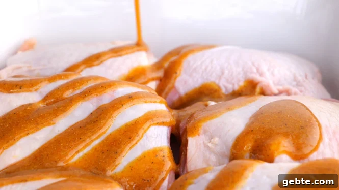 Crispy Honey Mustard Baked Chicken Thighs 2 Drizzling honey mustard over raw chicken thighs in a white baking dish.