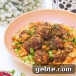 Meatballs piled on top of smoky red pepper sauce with flowers in the background.