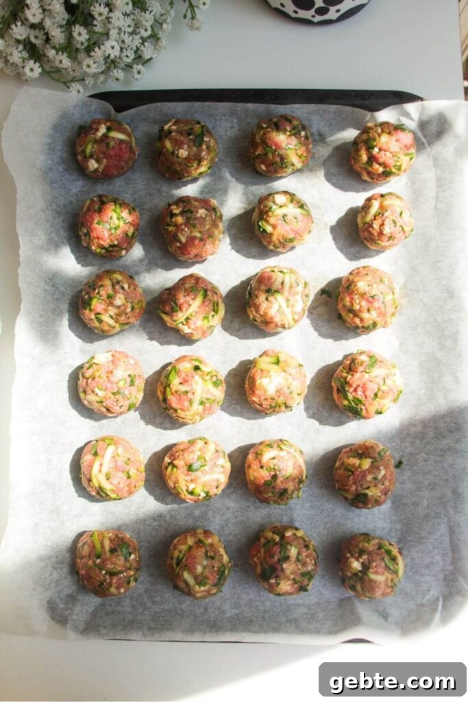 Rolled meatballs on a lined oven tray.
