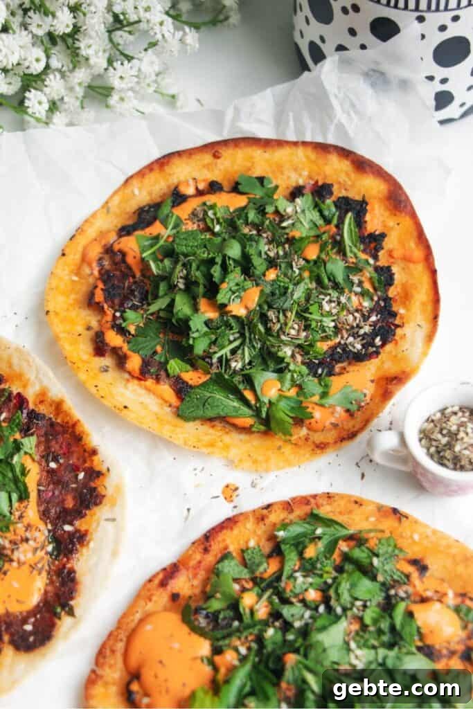 Smash lahmacun taco with red pepper sauce and herby salad on top.