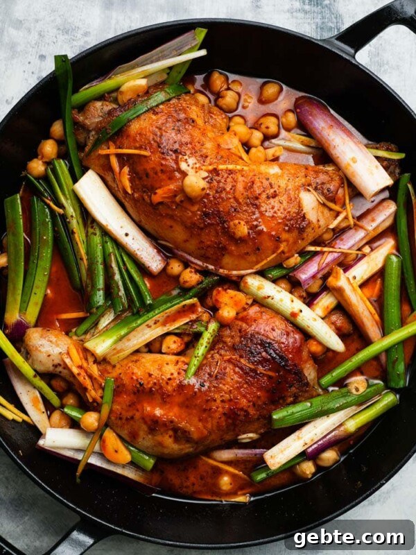 Gochujang glazed chicken with chickpeas and scallions in a black skillet.