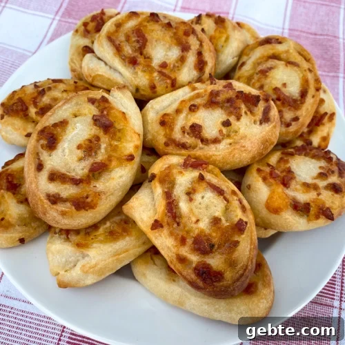White plate of pepperoni pinwheels stacked high on a red and white napkin.