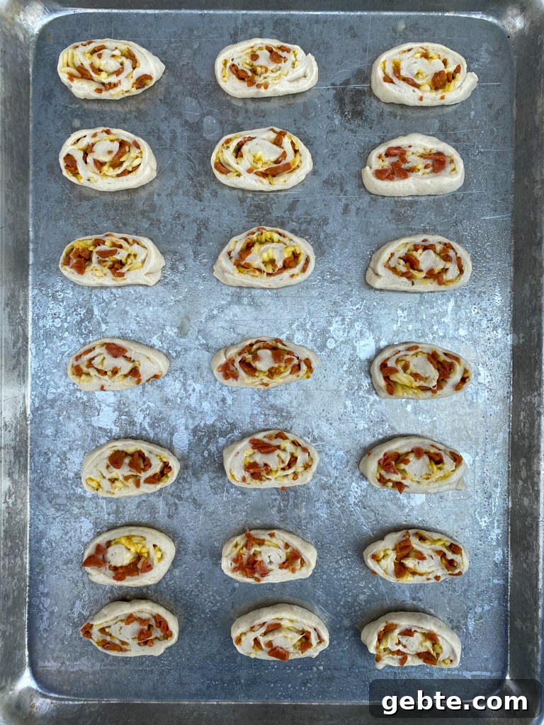 Sliced dough, filled and rolled up laying with the cut side up and arranged evenly on a large baking sheet.