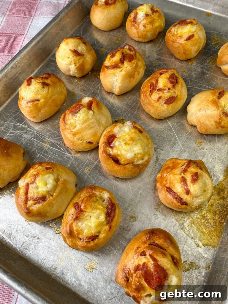 Thick pepperoni pinwheels baked with crescent dough on a baking sheet