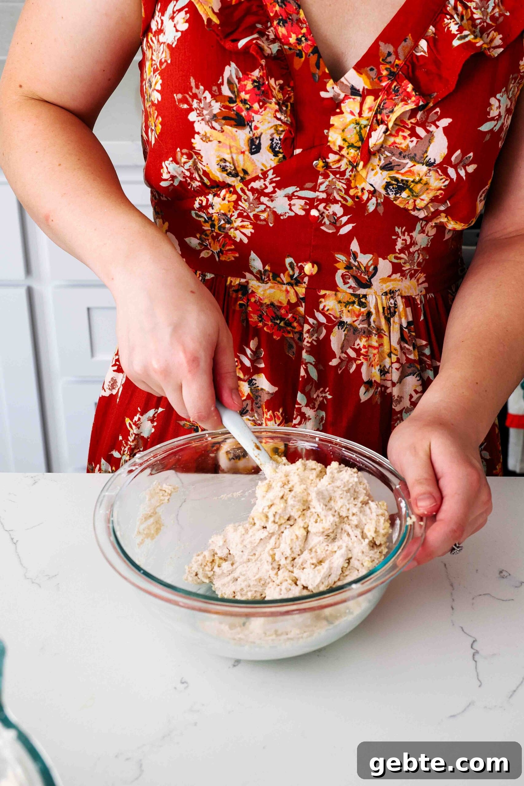A woman in a red dress stirs snickerdoodle cookie crumbs into cinnamon buttercream.