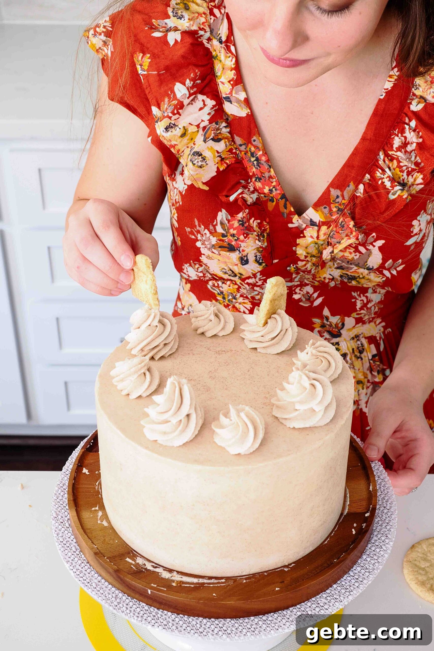 A woman adds wedges of snickerdoodle cookies on top of a cake.