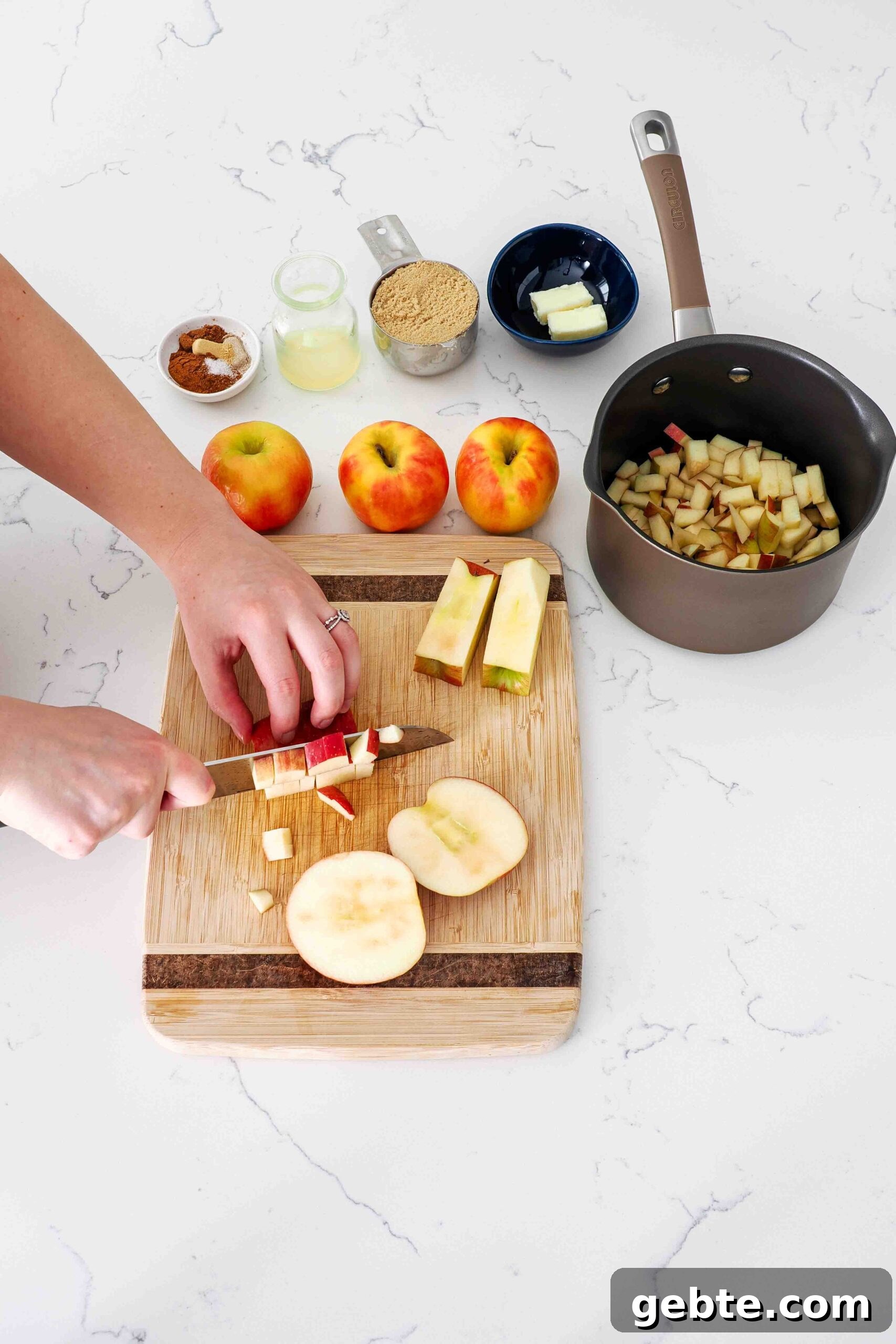 Two hands slice apples on a cutting board.