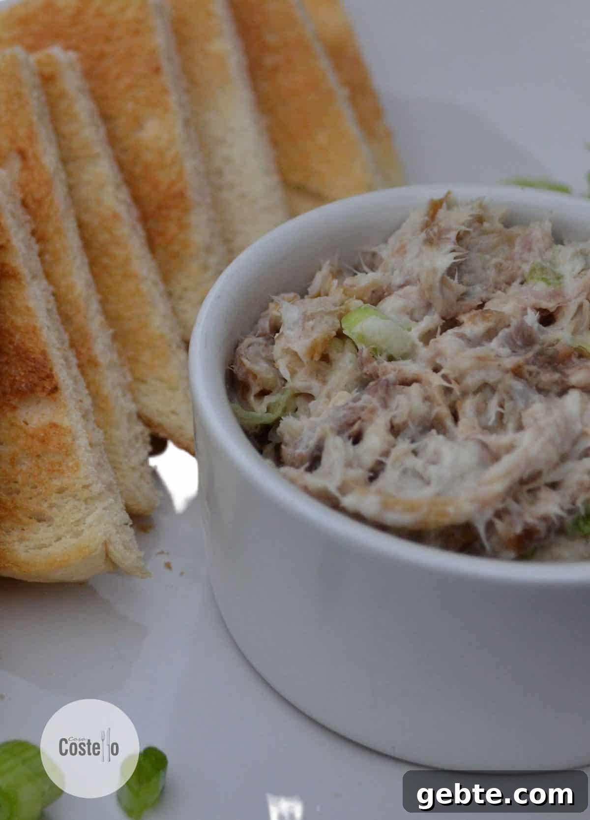 mackerel pate in a round white bowl with triangles of toast stacked next to it