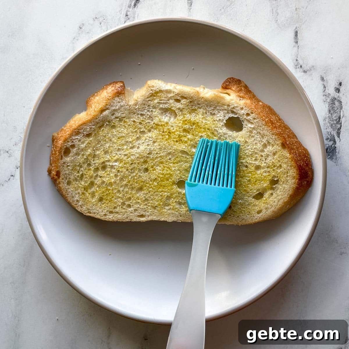 A piece of bread is brushed with olive oil.