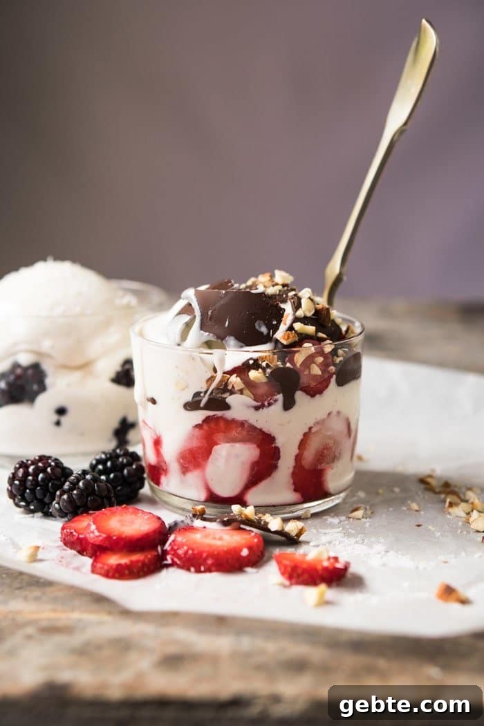 A glass with keto frozen yogurt, strawberries and a spoon