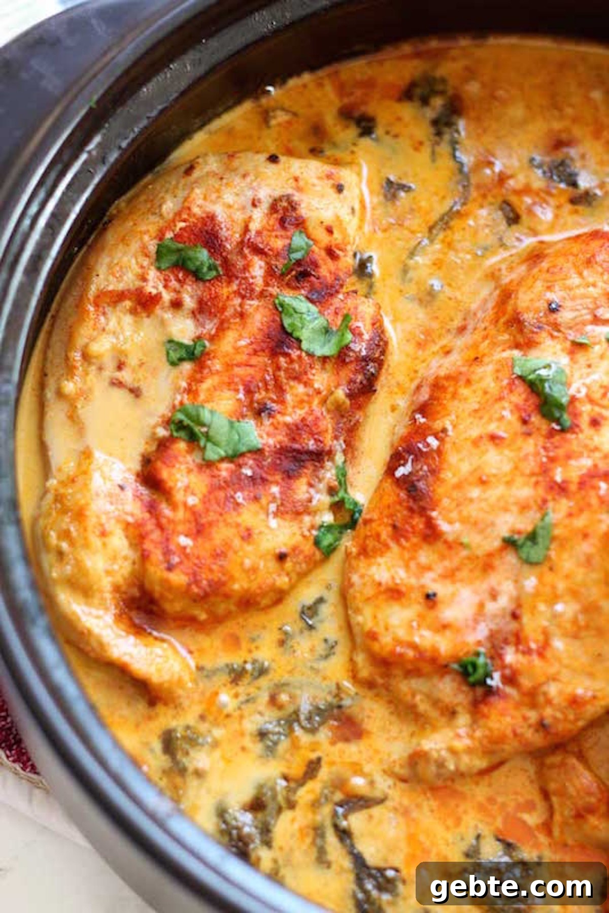 A skillet is filled with chicken breasts that have been seared, then cooked in a light orange lemon butter sauce.