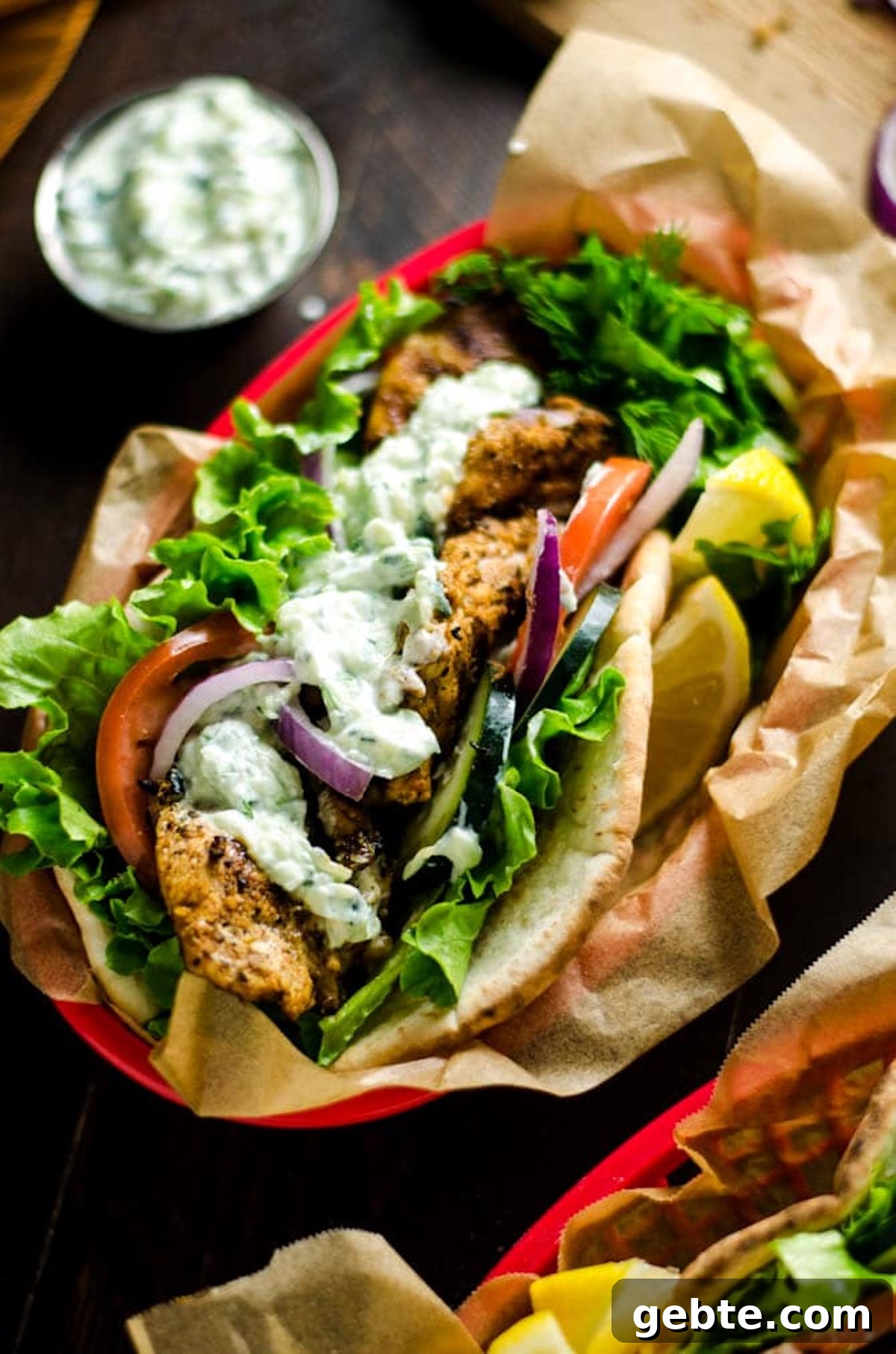 A plastic food basket has been lined with brown paper and a homemade gyro has been place on top with lemon wedges on the side.