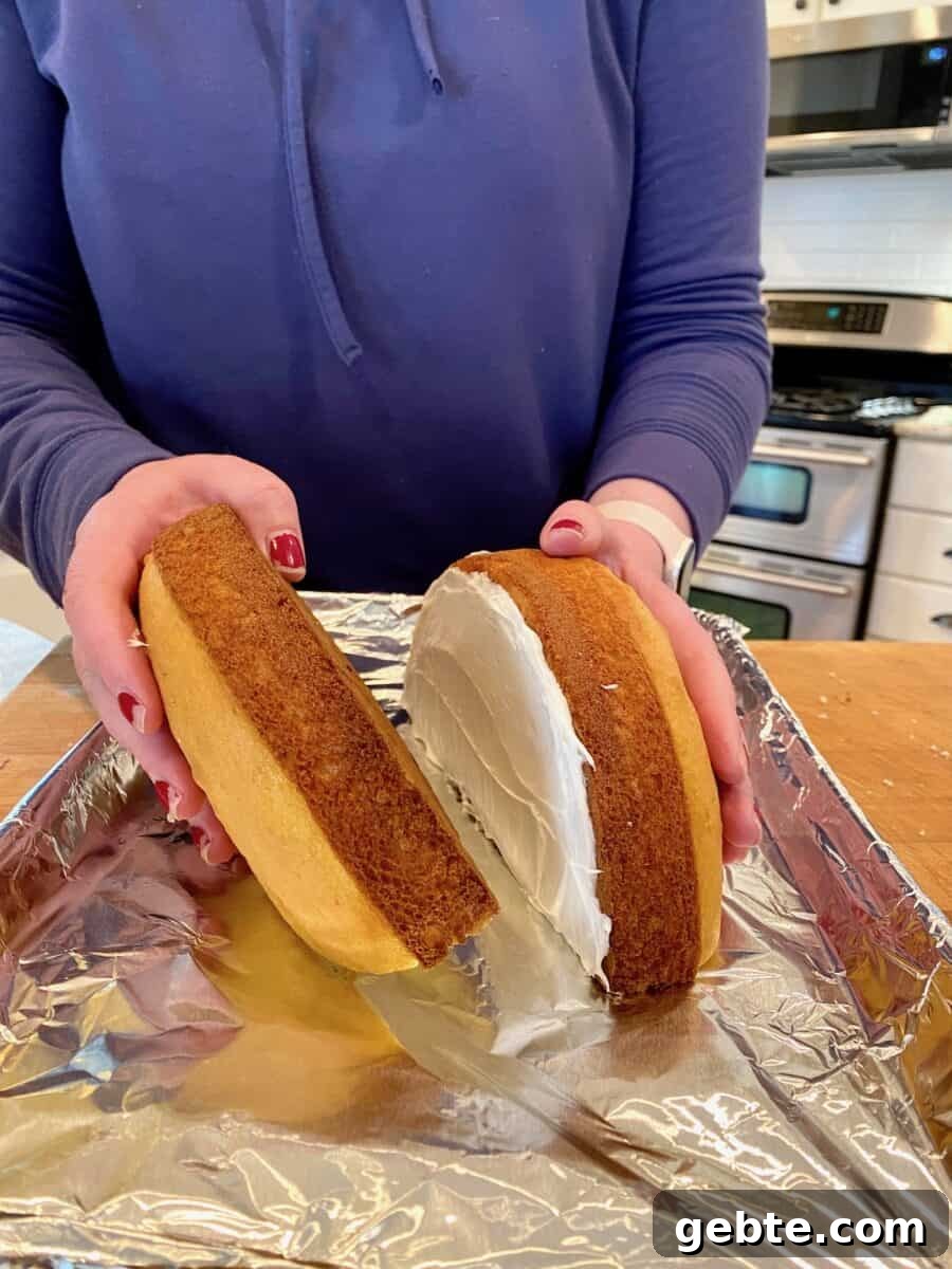 Frosting added onto two halves of round cakes.