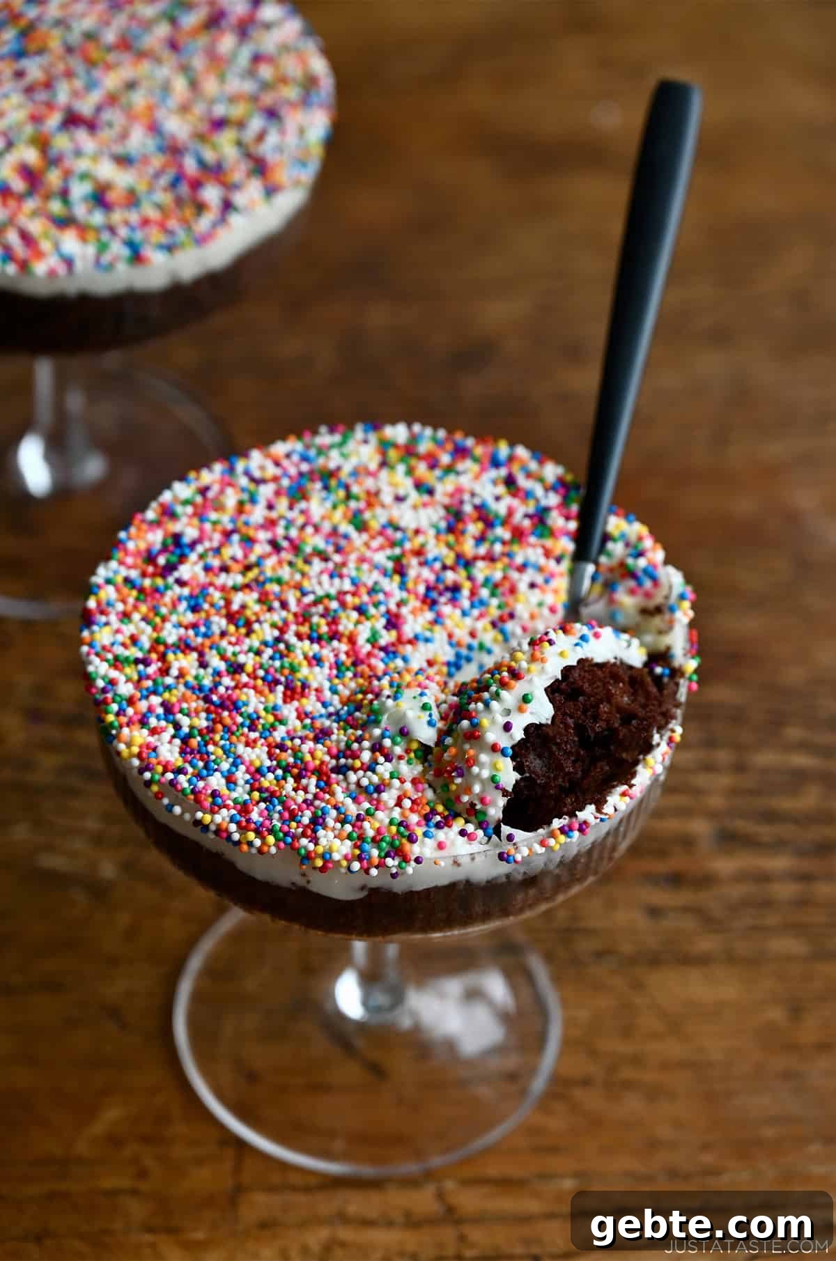 Homemade Polka Dot Cake Recipe 4 A spoon scooping out cake and frosting with rainbow nonpareils from a cocktail glass.