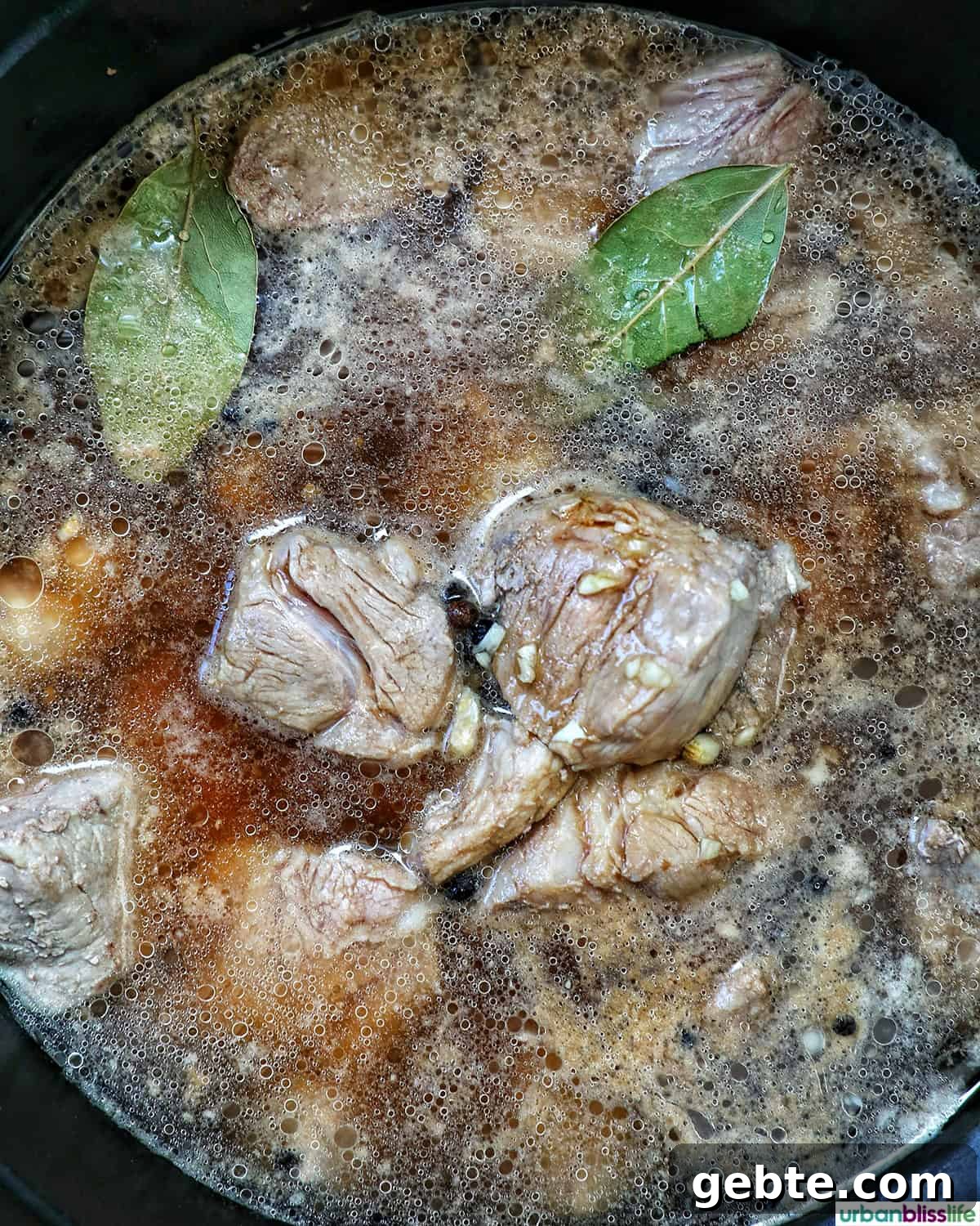 pork cooking in a pot with bay leaves.