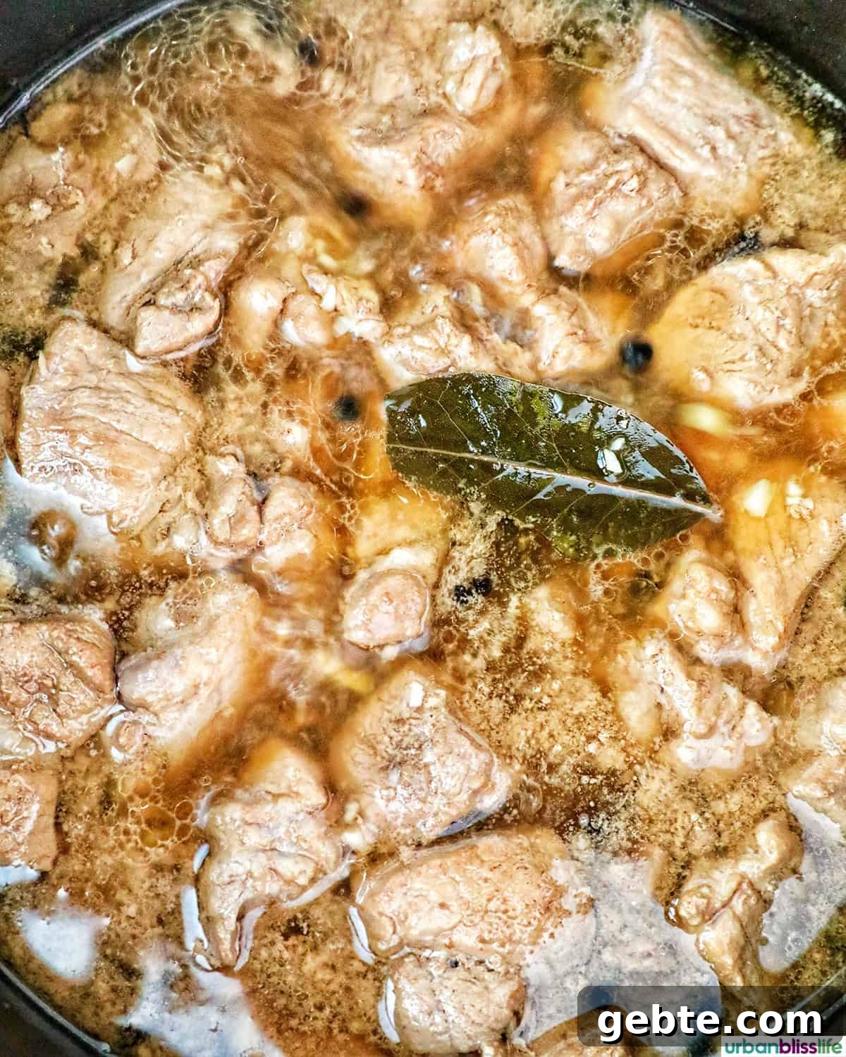 pork cooking in a pot with bay leaves.