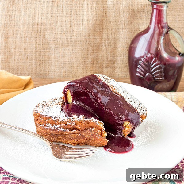 Crispy Deep Fried French Toast for Your Dream Brunch 3 A thick slice of french toast with pureed berry sauce on a white plate and a sprinkle of powdered sugar.