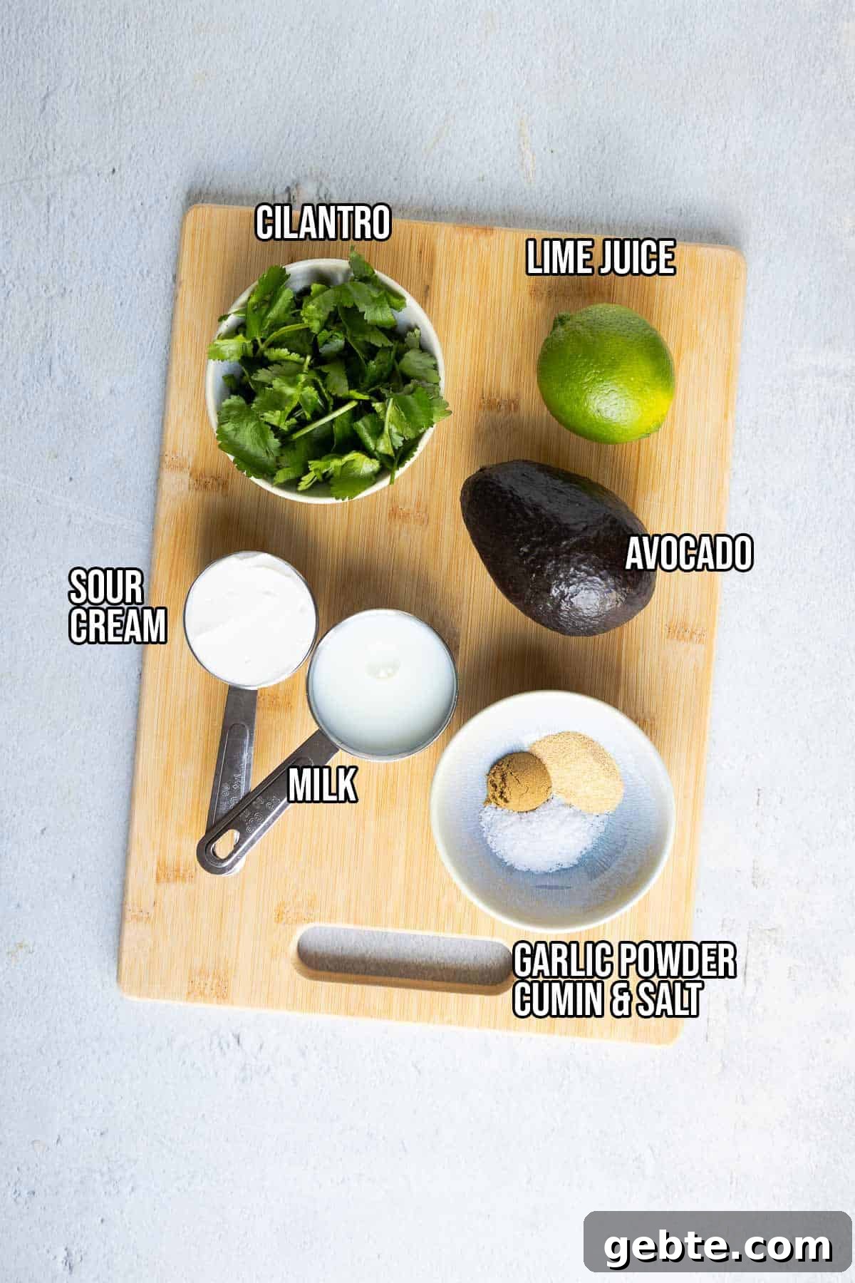 Avocado dressing ingredients: avocado, sour cream, lime, cilantro, milk, garlic powder, cumin, and salt.