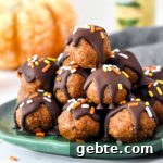 No-Bake Pumpkin Pie Date Balls: Fall Snack Recipe 10 no-bake pumpkin pie date balls stacked on a green plate.