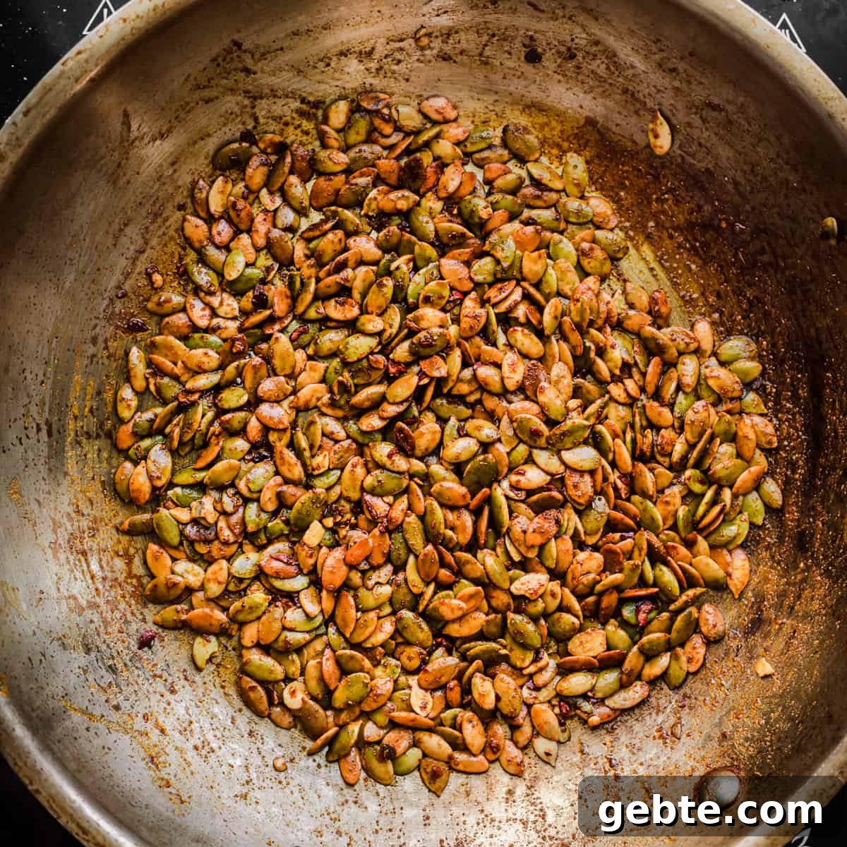 Oven-Roasted Carrots and Dates with Pistachio Pesto 11 Seed sprinkle ingredients in a frying pan after being cooked.