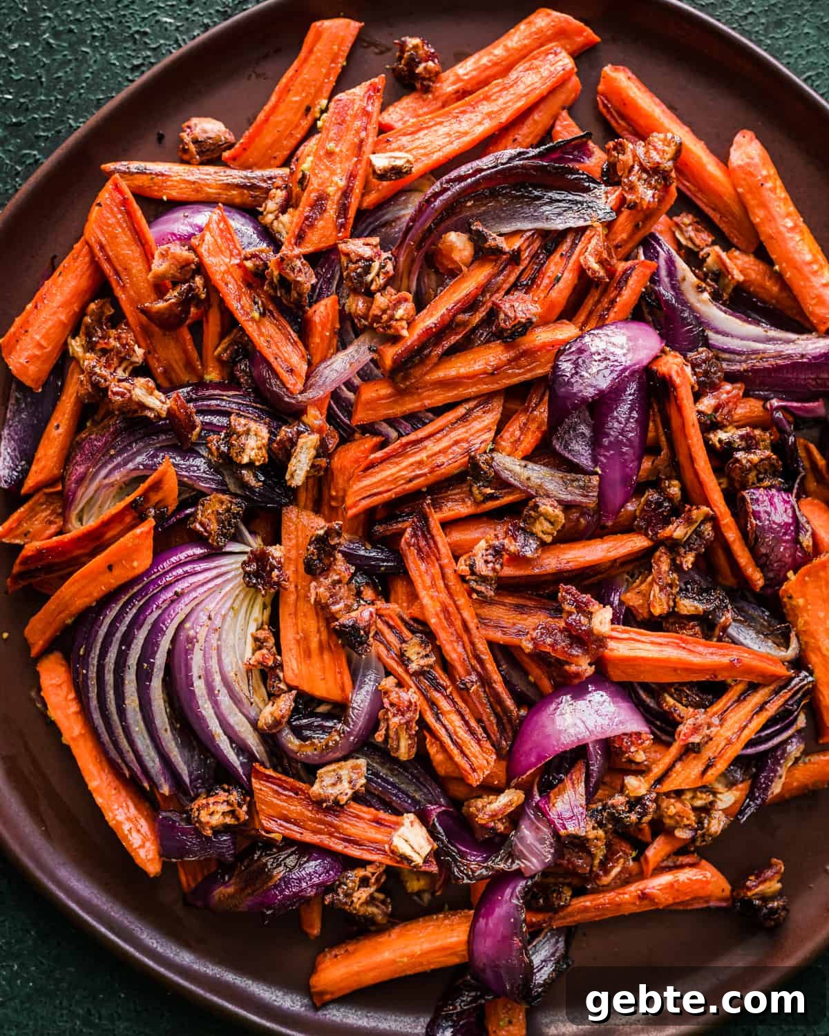 Oven-Roasted Carrots and Dates with Pistachio Pesto 12 Carrots, dates and onions on a brown plate.