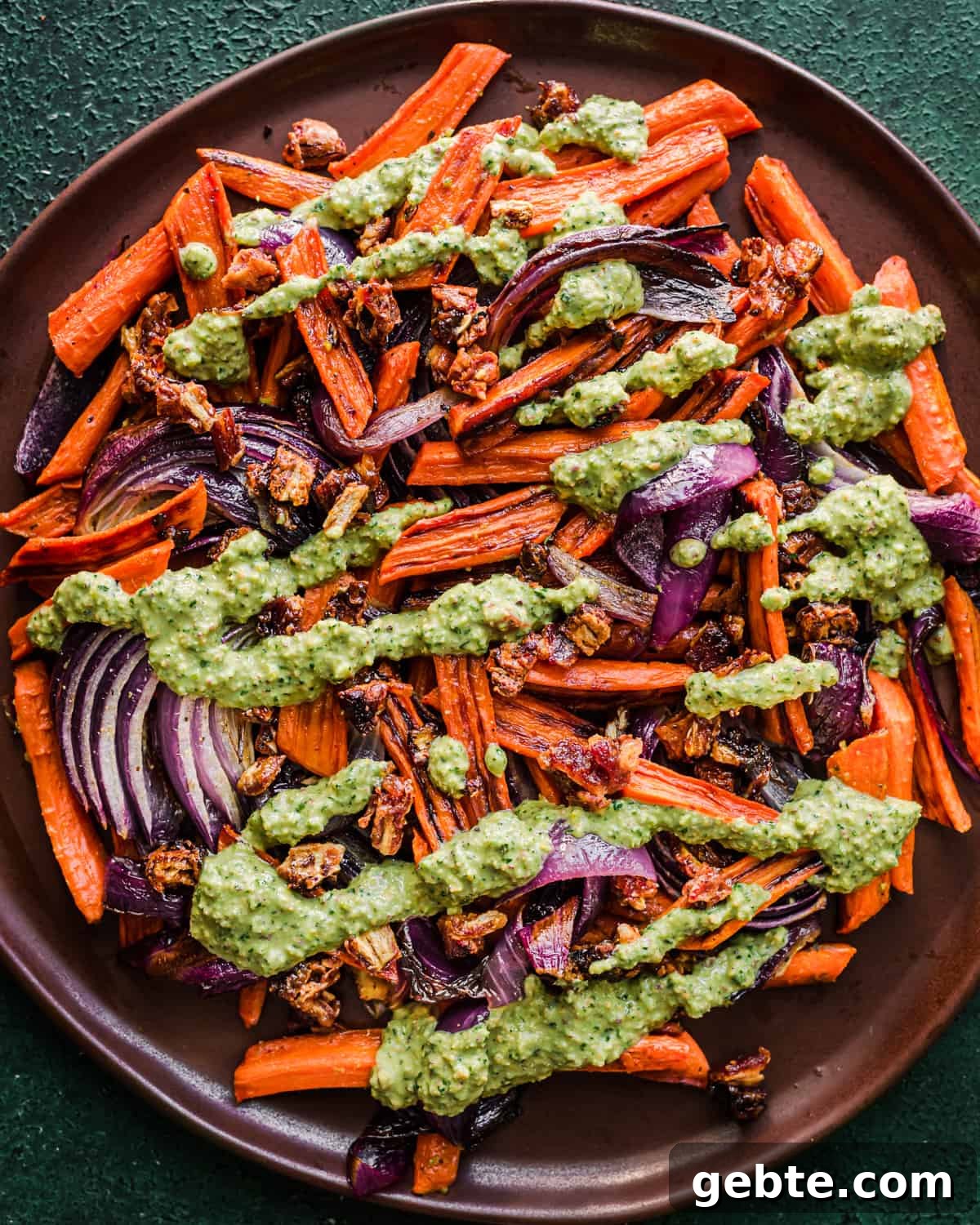 Oven-Roasted Carrots and Dates with Pistachio Pesto 13 Pesto added to the carrots, onions and dates on a plate.