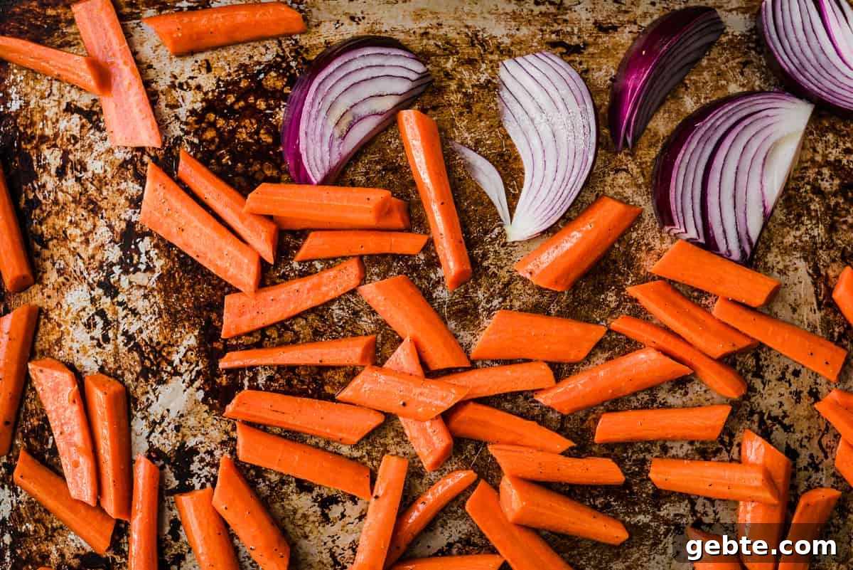 Oven-Roasted Carrots and Dates with Pistachio Pesto 6 Carrots and onions on a baking sheet before being roasted.